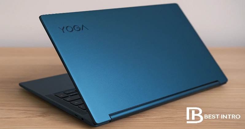 لپ‌تاپ لنوو Yoga 9i مدل Aura Edition با رنگ آبی کیهانی روی میز چوبی، همراه با لوگوی Best Intro در گوشه تصویر